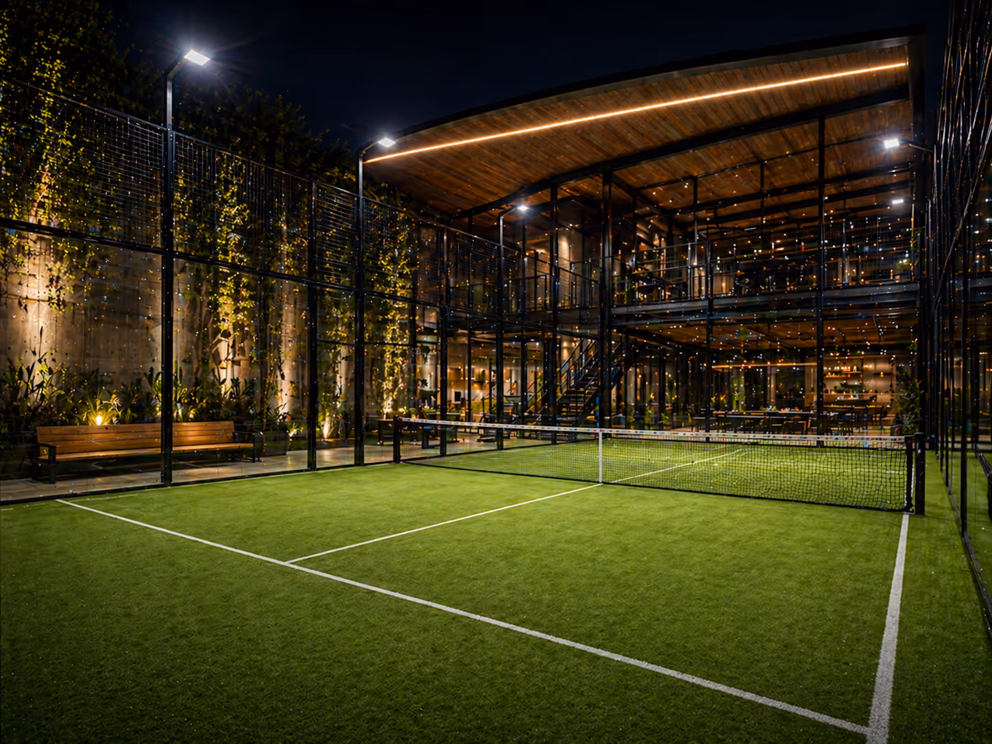 Floodlit turf court beside a lit pavilion at night